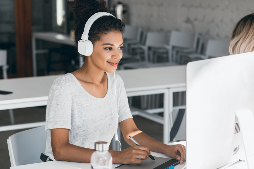 jeune femme brune souriante web designer devant son écran d'ordinateur