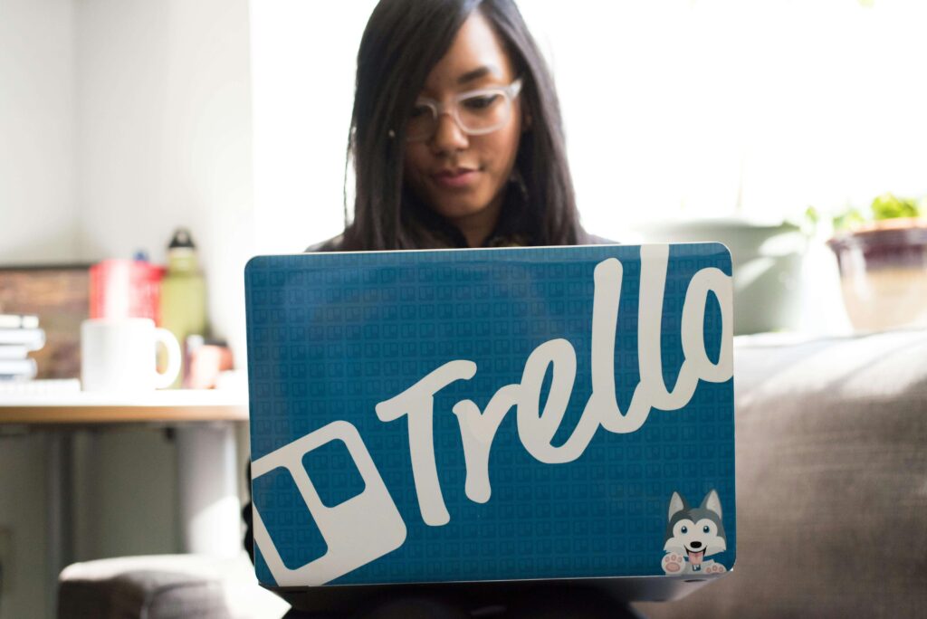 jeune femme freelance sur son ordinateur portable décoré du logo Trello.